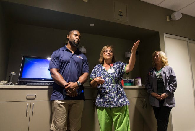 Brenda Lewis, radiation therapist, explains cancer treatment center equipment to former NFL running back Ahman Green Friday, Aug. 7, 2015, at Rockford Memorial Hospital. SUNNY STRADER/RRSTAR.COM