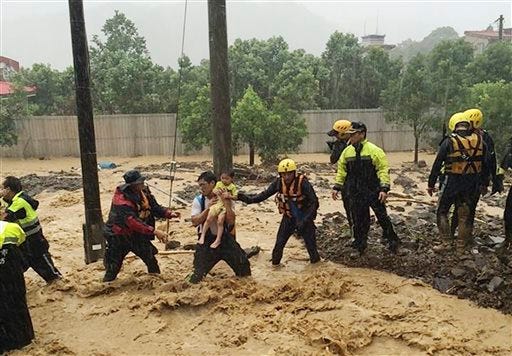 In this image released by the New Taipei Fire Department, emergency rescue personnel carry a child through a flash mudslide caused by Typhoon Soudelor in Xindian, New Taipei City, northern Taiwan, Saturday, Aug. 8, 2015. At least four people were killed and four were missing when powerful Typhoon Soudelor slammed into Taiwan, authorities said Saturday. (New Taipei Fire Department via AP)