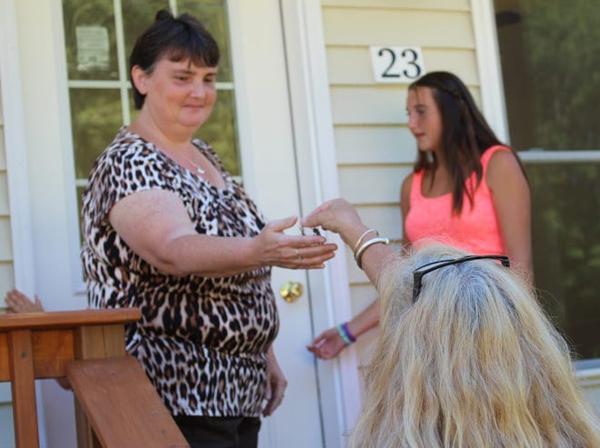 Southeast NH Habitat for Humanity Executive Director Marcie Bergan hands the keys to a new family home to Tracy Shavor as the new homeowner fights to hold back tears. Crystal A. Weyers photo