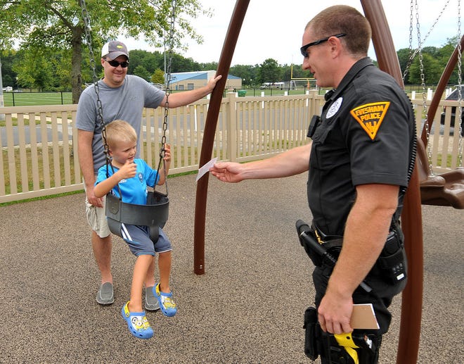 Evesham police Officer Jeremy Borden gives Brendan Kondrath, 4, of Mount Laurel, a beverage coupon at a playground next to the township police station Sunday. Officers ticketed children for good behavior.