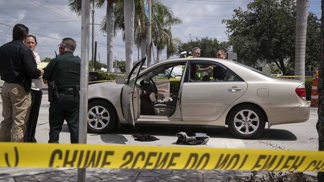 Investigators examine a Toyota Camry belonging to a shooting victim at the intersection of Lucerne Avenue and North G Street in Lake Worth Sunday, August 9, 2015. The victim drove himself to the police station there after being shot on Washington Avenue, PBSO reports. (Bruce R. Bennett / The Palm Beach Post)
