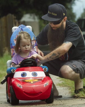 Ava Brown, 18-months old, plays with her father Jeremy Brown, 31, outside their home in Winter Haven Thursday. Brown was born with cerebral palsy and movement, for her, has always been a challenge. She was provided a motorized car by the Go Baby Go campaign.