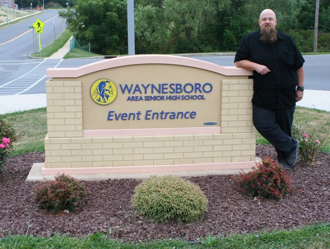 Local singer/songwriter Rich Fehle stands at the entrance to the Waynesboro Area Senior High School where a concert featuring country star John Berry will be held on Friday evening to benefit the Waynesboro band program.
