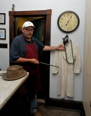 John Groze shows the hat, coat and saw of John Szucs, founder of Szucs Meat Market in Roebling. The items are on display in the family-owned store.
