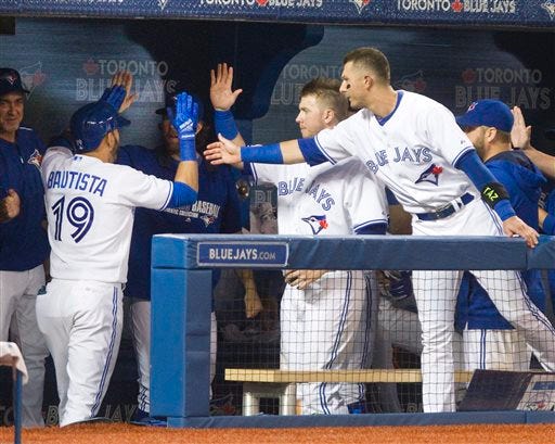 Toronto Blue Jays' Jose Bautista is congratulated by teammates in the dugout after he hit a solo home run against the Oakland Athletics during the fifth inning of a baseball game Tuesday, Aug. 11, 2015, in Toronto. (Fred Thornhill/The Canadian Press via AP)