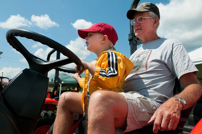 Victor Kalnajs, 3, of Hatboro gets a feel for a new tractor outside the R&S Equipment tent with his grandfather, Juris Kalnajs of Horsham on opening day of the annual Middletown Grange Fair in Wrightstown Wednesday, August 12, 2015.