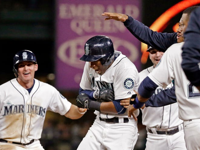 Seattle Mariners' Austin Jackson, center, is mobbed by teammates after hitting in the game-winning run against the Baltimore Orioles in the 10th inning of a baseball game Tuesday, Aug. 11, 2015, in Seattle. The Mariners won 6-5.