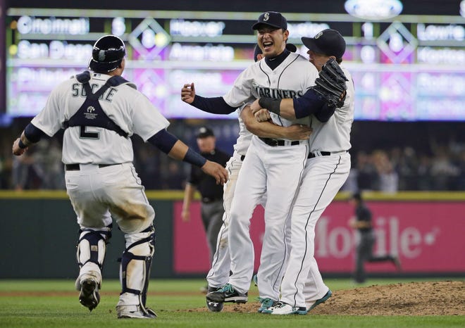 The Seattle Mariners' Hisashi Iwakuma is greeted by teammates, including catcher Jesus Sucre, left, after Iwakuma threw a no-hitter against the Baltimore Orioles on Wednesday. The Associated Press
