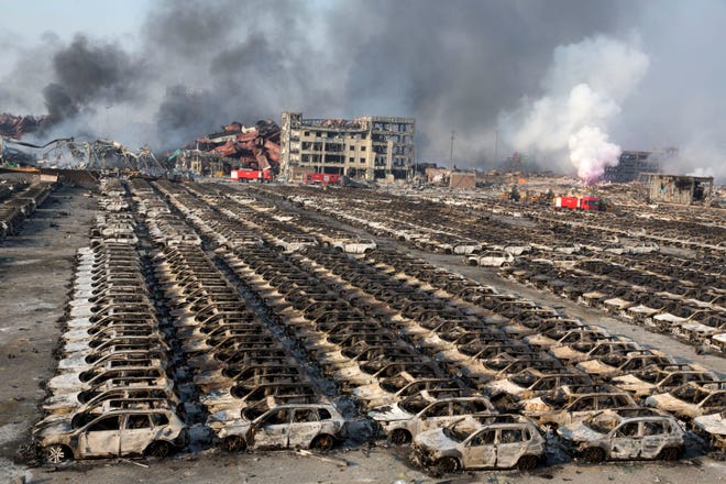 Smoke billows from the site of an explosion that reduced a parking lot filled with new cars to charred remains at a warehouse in northeastern China's Tianjin municipality Thursday. Huge explosions in the warehouse district sent up massive fireballs that turned the night sky into day in the Chinese port city of Tianjin, officials and witnesses said Thursday.