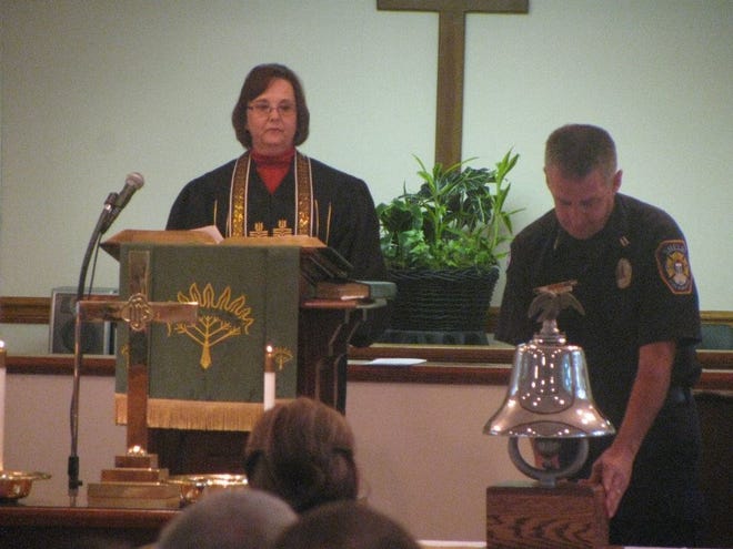 During last years' service at John Knox Presbyterian Church in Shelby, Pastor Deborah Lesenger looks on as an official with Shelby Fire and Rescue rings a bell in memory of firefighters who died on duty.