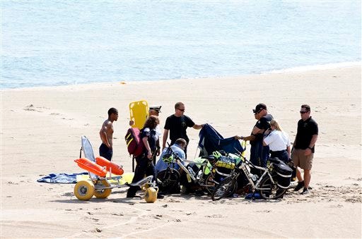 A Navy Leap Frog parachutist receives medical attention on North Avenue Beach on Saturday, Aug. 15, 2015, after a performance at the first day of the annual Chicago Air & Water Show in Chicago. (Michael Noble Jr./Chicago Tribune via AP)