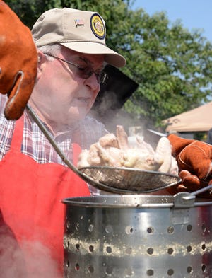 Lee Stroud lifts a scoop of chicken wings, ready to be grilled, Friday at the Kinston-Lenoir County Farmer’s Market during the seventh annual Wings Over the Neuse fundraiser for the CSS Neuse II.