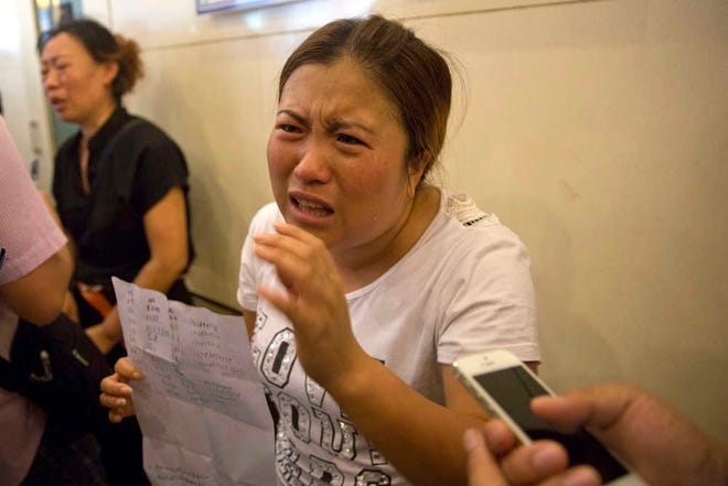 Wang Baoxia talks to a journalist about her missing brother Wang Quan who was at the scene of an explosion in northeastern China's Tianjin municipality, Saturday, Aug. 15, 2015. Angry family members of firefighters missing in the explosions that rocked the Chinese port city of Tianjin stormed a government news conference on Saturday, demanding information on their loved ones. (AP Photo/Ng Han Guan)