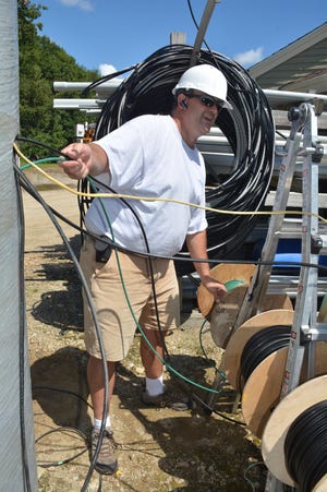 Mark Ayotte, of Ayacht Technology, feeds cable to his crew as they repair the WiMax internet service atop the communication tower at the Princeton Municipal Light Department. The equipment was damaged by a lightning strike. Photo/Chris Christo