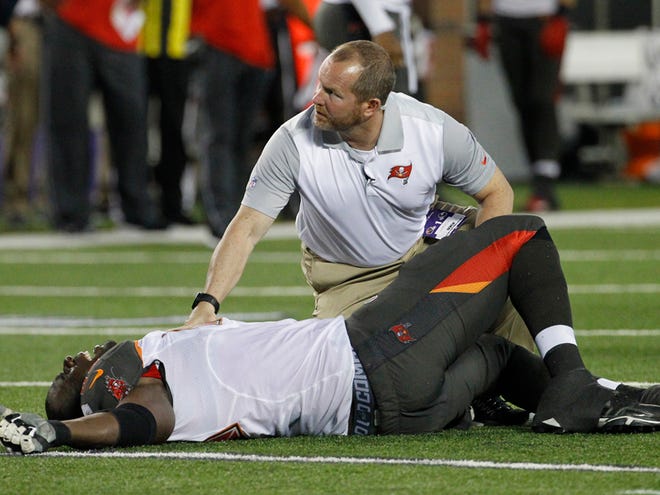 A trainer attends to Tampa Bay Buccaneers tackle Demar Dotson after being injured against the Minnesota Vikings during a preseason NFL football game at TCF Bank Stadium Saturday, Aug. 15, 2015, in Minneapolis.