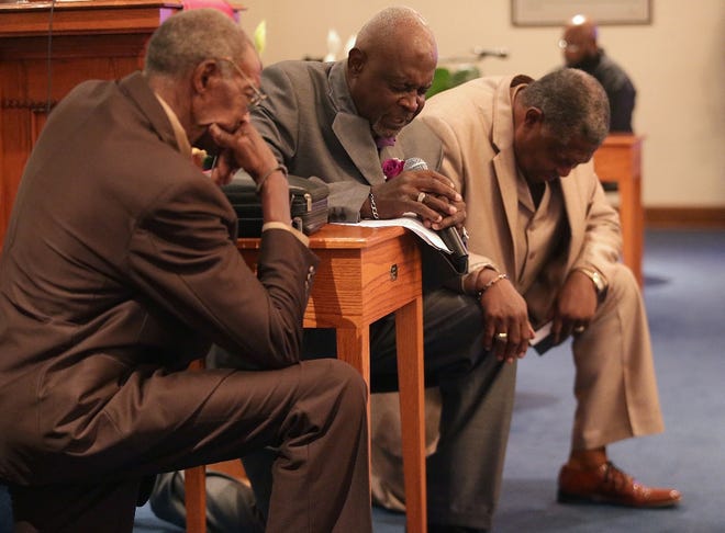 Deacons Fred Peterson, Robert Smith and Clem Pinckney kneel in prayer during First Mount Moriah Missionary Baptist Church's centennial celebration Sunday, Aug. 17, in Springfield.