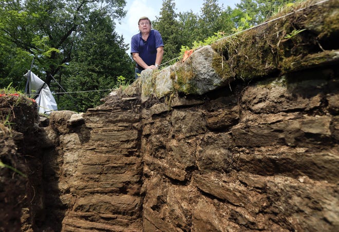 Archaeologist David Starbuck poses near a stone wall unearthed at Lake George Battlefield Park on Monday, Aug. 17, 2015, in Lake George, N.Y. An archaeological dig at the 18th-century military site in the southern Adirondacks has uncovered large sections of stone walls that are believed to have been constructed within a larger British fortification that was never completed more than 250 years ago. (AP Photo/Mike Groll)