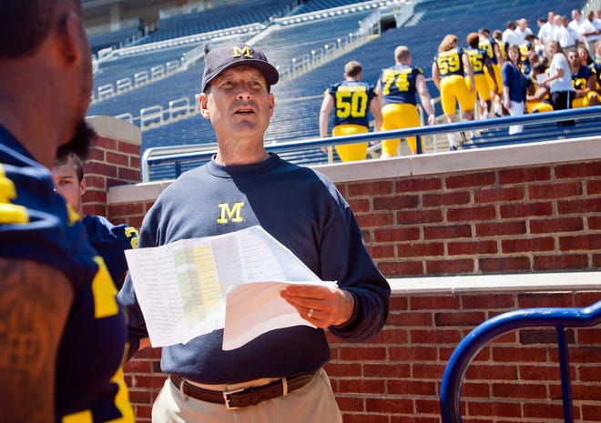 Michigan head coach Jim Harbaugh coordinates his players to lineup in the Michigan Stadium stands for a team photo, during the NCAA college football team's annual media day in Ann Arbor, Mich., Thursday, Aug. 6, 2015. (AP Photo/Tony Ding)