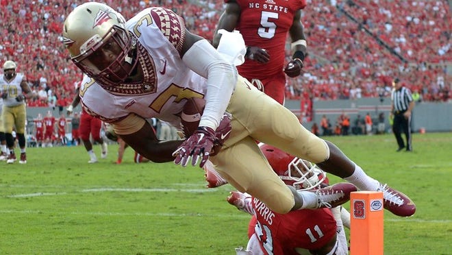 RALEIGH, NC - SEPTEMBER 27: Jesus Wilson #3 of the Florida State Seminoles dives over Juston Burris #11 of the North Carolina State Wolfpack for a tochdown during their game at Carter-Finley Stadium on September 27, 2014 in Raleigh, North Carolina. Florida State won 56-41. (Photo by Grant Halverson/Getty Images)