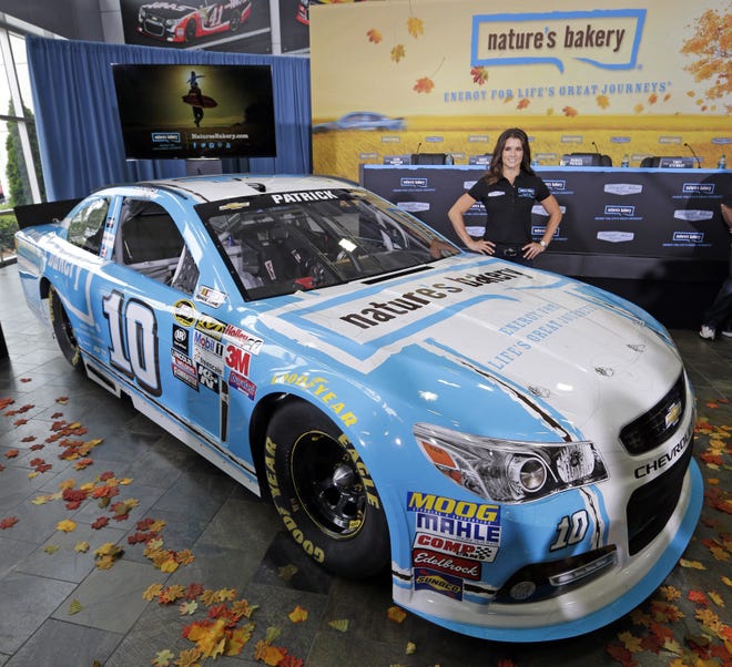 Danica Patrick poses by her new race car during a news conference to announce a new sponsorship for her NASCAR auto racing team at Stewart-Haas Racing's headquarters in Kannapolis, N.C., Tuesday, Aug. 18, 2015. (AP Photo/Chuck Burton)