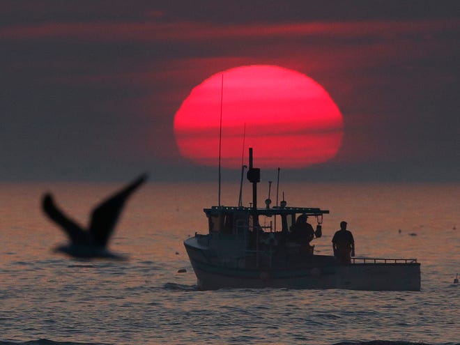 A lobster boat heads out to sea at sunrise, off Kennebunkport, Maine.