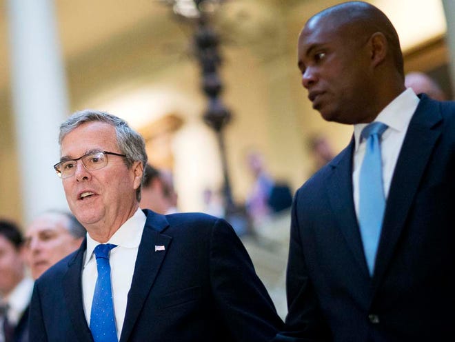 Former Florida Gov. Jeb Bush, left, walks with former campaign staff member Rufus Montgomery, right, while visiting the Georgia Capitol, Thursday, March 19, 2015, in Atlanta. Tallahassee's mayor and a half-dozen state legislators called for Montgomery to step down from the Florida A&M University Board of Trustees.