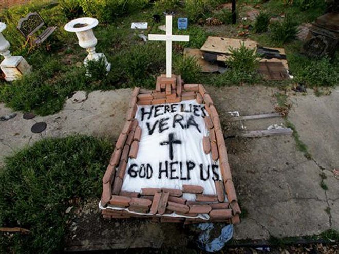 FILE - In this Sept. 4, 2005, file photo, a makeshift tomb at a New Orleans street corner conceals a body that had been lying on the sidewalk for days in the wake of Hurricane Katrina. The message reads, "Here lies Vera. God help us." Smith's cremated remains were later reburied in Texas, yet she remains part of her old community.