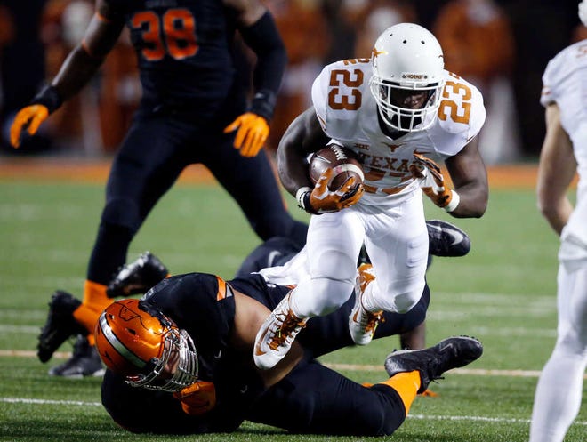 FILE - In this Nov. 15, 2014, file photo, Texas's Daje Johnson (23) is tripped by an Oklahoma State defender in the first quarter of an NCAA college football game in Stillwater, Okla. For three years, Johnson has been the great hope and the great disappointment for Texas. The playmaker with the blazing speed and shifty moves has spent most of his career teasing fans with a few touchdowns in between long stints on the bench or under suspension. Now he's up against his last chance at Texas. And he knows it. (AP Photo/Sue Ogrocki, File)