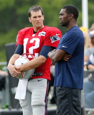 New England Patriots quarterback Tom Brady, left, talks with former wide receiver Randy Moss, right, during a joint practice between the Patriots and New Orleans Saints at the Saint's NFL football training camp in White Sulphur Springs, W.Va., Thursday, Aug. 20, 2015.