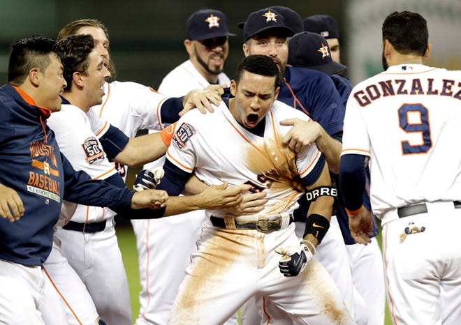 Houston Astros' Carlos Correa, center, is mobbed by teammates after hitting a walk-off RBI in the 13th inning of a baseball game to beat the Tampa Bay Rays 3-2, Wednesday, Aug. 19, 2015, in Houston. (AP Photo/Pat Sullivan)
