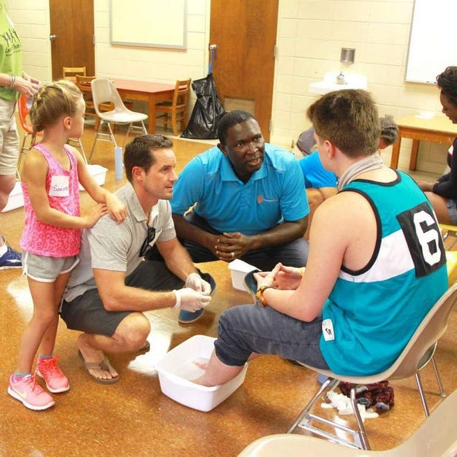 NASCAR's Casey Mears and Manny Ohonome from Samaritan's Feet wash the feet of a foster child.