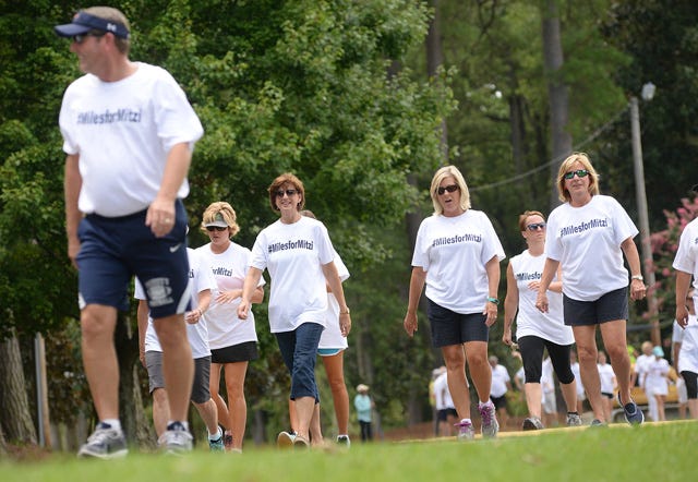 Faculty and staff at Arendell Parrott Academy run and walk around the school grounds Thursday as they complete the Miles for Mitzi campaign in honor of college advisor Mitzi Moye, who was injured in a June accident.