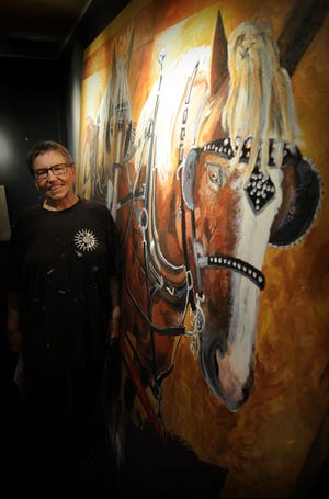 Photos by TOM DORSEY / Salina Journal Lindsborg artist Lee Becker stands next to her 85-by-98-inch acrylic painting “Team of Belgians” on display in The Gallery at Kansas Wesleyan University. Becker often tries to paint animals in life-size dimensions. Her work will be on display through Sept. 11.