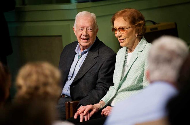 Former President Jimmy Carter, left, sits with his wife Rosalynn as they pose for photos after Carter taught Sunday School class at Maranatha Baptist Church in his hometown Sunday, Aug. 23, 2015, in Plains, Ga. The 90-year-old Carter gave one lesson to about 300 people filling the small Baptist church that he and his wife, Rosalynn, attend. It was Carter's first lesson since detailing the intravenous drug doses and radiation treatment planned to treat melanoma found in his brain after surgery to remove a tumor from his liver. (AP Photo/David Goldman)