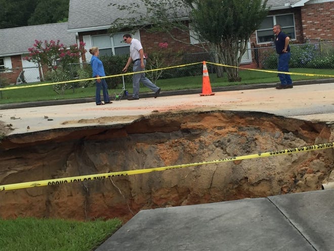 City workers take measurements near a sinkhole that opened on Iowa Avenue in Groveland.