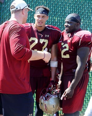 At Boston College football practice Thursday, Aug. 13, 2015, safety Justin Simmons, center, and linebacker Steven Daniels, right, speak with a coach on the sidelines.