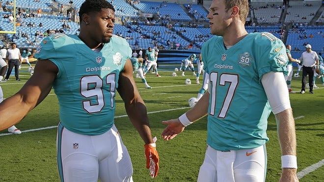 Miami Dolphins' Ryan Tannehill (17) talks with Cameron Wake (91) before an NFL preseason football game against the Carolina Panthers in Charlotte, N.C., Saturday, Aug. 22, 2015. (AP Photo/Bob Leverone)