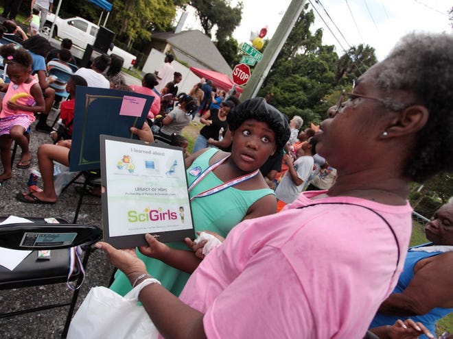 Joeann Johnson, left, admires the certificate Melandra Johnson received for participating in the SciGirls program hosted by the Porters community.
