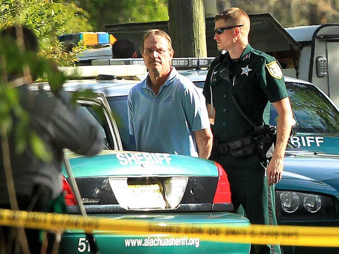 In this April 1, 2014 file photo, a deputy with the Alachua County Sheriff's Office detains Randall J. Smith in connection with a shooting on Northwest 69th Drive in Gainesville.