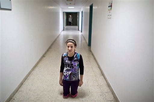 In this Tuesday, Aug. 11, 2015 photo, Syrian girl Salam Rashid, 14, who lost both of her legs below the knee in 2012 in a tank shell attack, poses for a picture at the MSF Hospital for Specialized Reconstructive Surgery in Amman, Jordan. The international charity MÃ©decins Sans FrontiÃ¨res (Doctors Without Borders) officially inaugurates in Amman next month its new reconstructive surgery hospital for war victims, which it says is unique in the region. (AP Photo/Muhammed Muheisen)
