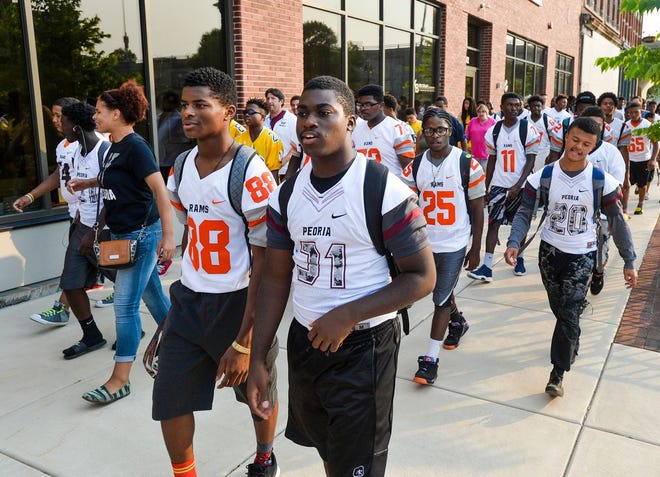 Manual Academy and Central High football players walks together down Washington Street during Thursday's Peace Walk.