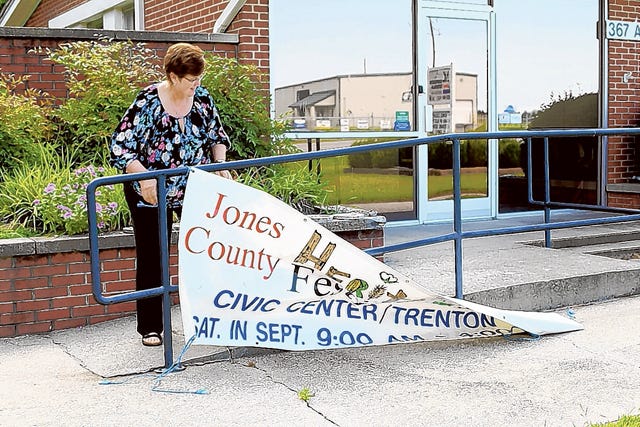 Ivy Reid hangs the original Heritage Festival banner outside of the Jones County Cooperative Extension Office on Monday. This year's event will start at 10 a.m. Sept. 19.