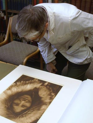 Lesli Larson, director of library communications at the UO, is transfixed by a Curtis photograph of an Aleutian woman, Ola Noatak. (Randi Bjornstad/the Register-Guard)