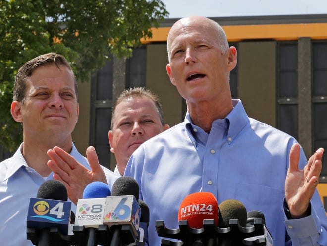 Gov. Rick Scott, right, talks to reporters at the Miami-Dade State Emergency Operations Center as Lt. Gov. Carlos Lopez-Cantera, left, looks on Friday, Aug. 28, 2015, in Doral, Fla.