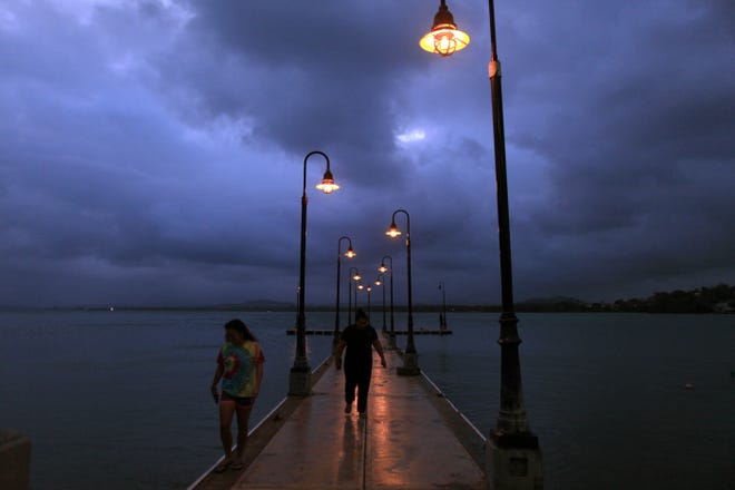 A couple walks on a pier as Tropical Storm Erika approaches Naguabo, Puerto Rico, Thursday. The Associated Press