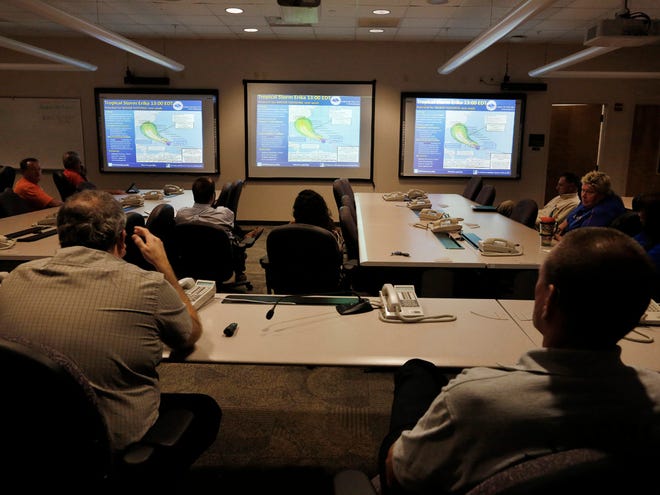 Dave Donnelly, left, the emergency management director of Alachua County, and Chief Bill Northcutt, right, of Alachua County Fire-Rescue, attend a discussion about Tropical Storm Erika at the Alachua County Communications & Emergency Operations Center Friday.