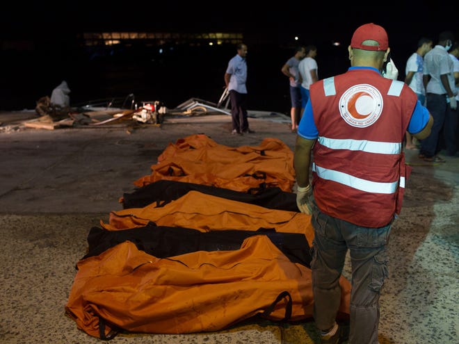 In this Thursday, Aug. 27, 2015 photo, rescuers gather around the bodies of drowned migrants in Zuwara, Libya.