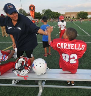 RV Patriot Head Team Mother Nicole Saucier gives Carmello Anderson, 7, a high five after he scores a touchdown Saturday evening at the Westamtpon Sports Complex.