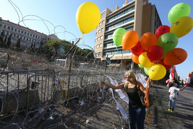 A Lebanese anti-government protester hangs a balloon on barbed wire in front the government building, during a demonstration against the trash crisis and government corruption, in downtown Beirut, Lebanon, Saturday. The Associated Press
