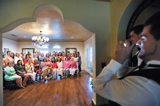 Photos by Will.Dickey@jacksonville.com Banquet server Neno Bijelic (right) takes a group photo of Phi Mu sorority alumnae during a tea celebrating the local chapter's 75th anniversary on Sunday at Epping Forest Country Club.